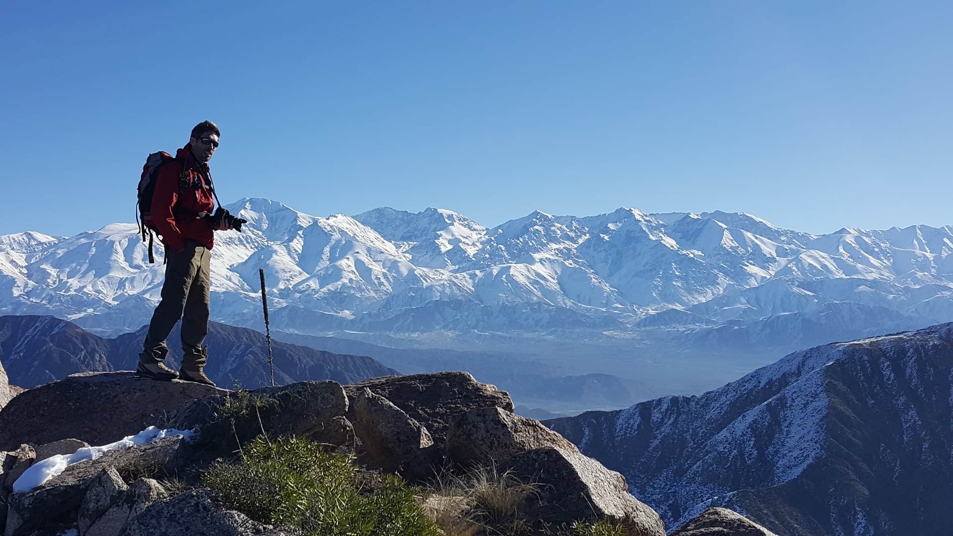 Imagen de un escalador sobre la cumbre de un cerro disfrutando la vista